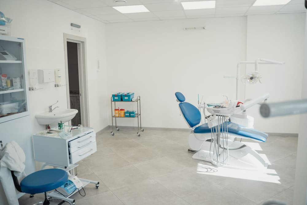 A dental room with a blue chair and wide windows
