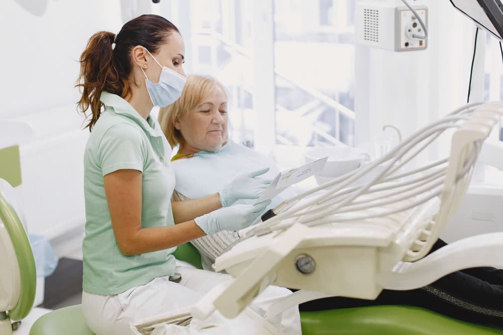 A dentist talking with an older patient in the chair